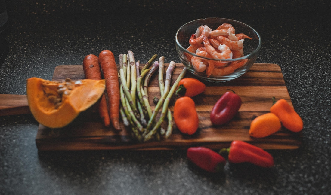 a wooden cutting board topped with carrots and asparagus