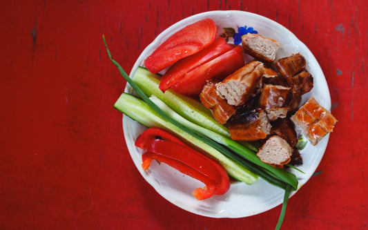 A plate contains grilled meat, tomatoes, and vegetables.