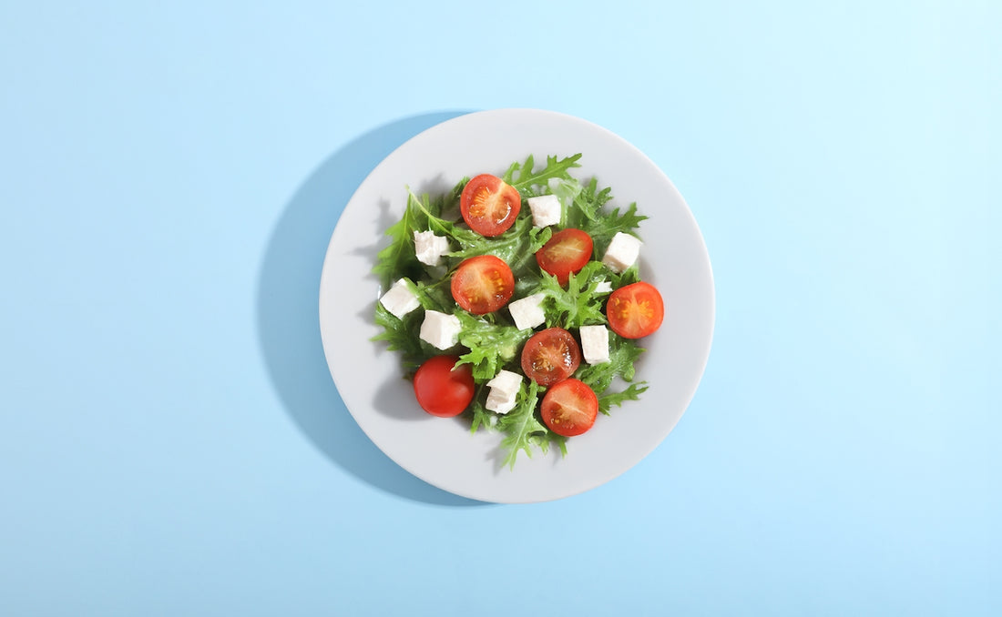 A plate of fresh salad with tomatoes and cheese.